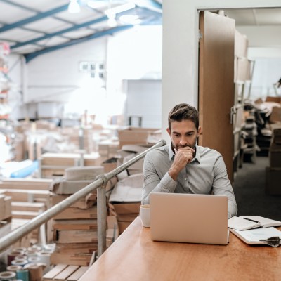 Produktsicherheitsverordnung (GPSR) 2024 - Was Unternehmen jetzt wissen müssen: Manager, der online arbeitet, während er in einem Lagerbüro sitzt 