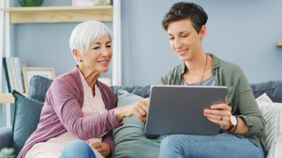 Digitaler Nachlass - Was passiert mit Online-Konten im Todesfall?: Ältere Frau und Tochter sitzen auf Sofa und besprechen etwas auf dem Tablet
