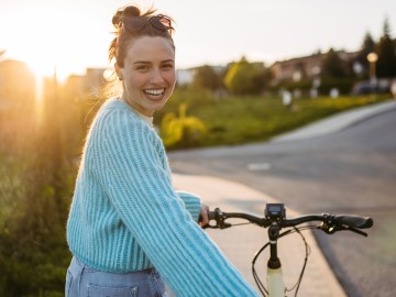Schäden clever beheben - Mehr Geld bei Reparatur: Junge Frau mit Pedelec lächelt