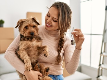 Frau zeigt ihrem Hund den neuen Wohnungsschlüssel