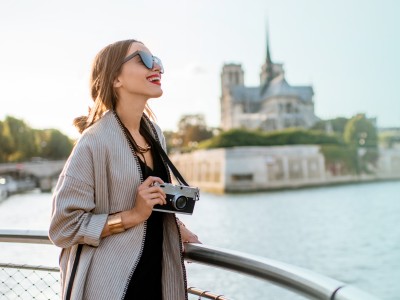 Alleine reisen - Tipps für den Urlaub alleine: Frau steht mit Kamera an der Seine