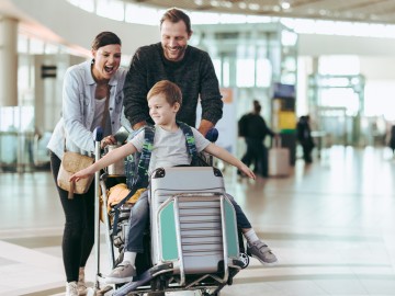 Reisegepäck verloren – wer haftet?: Familie mit Kind schiebt Koffer am Flughafen