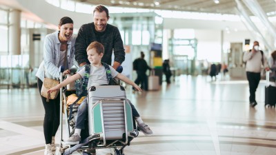 Reisegepäck verloren – wer haftet?: Familie mit Kind schiebt Koffer am Flughafen
