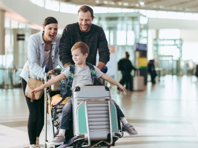 Reisegepäck verloren – wer haftet?: Familie mit Kind schiebt Koffer am Flughafen