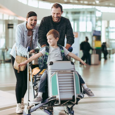 Reisegepäck verloren – wer haftet?: Familie mit Kind schiebt Koffer am Flughafen