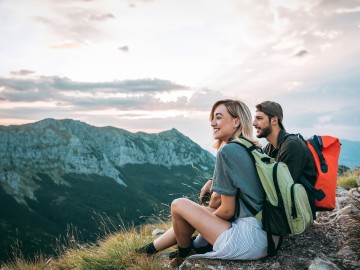 Reisetrend Coolcation - Abkühlung statt Hitzeschlacht: Ein Paar macht in den Bergen bei einer Wanderung eine Pause