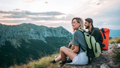 Reisetrend Coolcation - Abkühlung statt Hitzeschlacht: Ein Paar macht in den Bergen bei einer Wanderung eine Pause