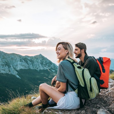 Reisetrend Coolcation - Abkühlung statt Hitzeschlacht: Ein Paar macht in den Bergen bei einer Wanderung eine Pause