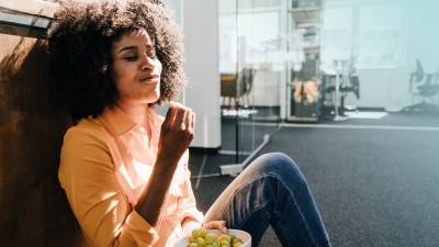 Fastenzeit - Was bringt es der Gesundheit?: Frau isst im Büro genüsslich Trauben