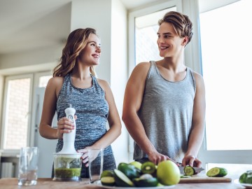 Jung und unbeschwert? So denken junge Erwachsene über ihre Gesundheitsvorsorge : Junges sportliches Paar kocht gesund