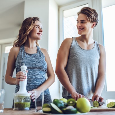 Jung und unbeschwert? So denken junge Erwachsene über ihre Gesundheitsvorsorge : Junges sportliches Paar kocht gesund