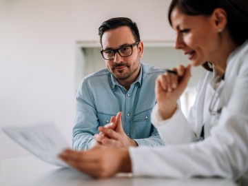 Der deutsche Krankenhausatlas - Was bringt die neue Online-Plattform?: Ärztin schaut gemeinsam mit männlichem Patienten auf Untersuchungsergebnisse auf einem Blatt Papier.