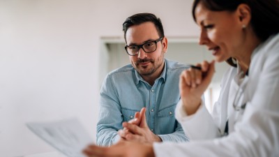 Der deutsche Krankenhausatlas - Was bringt die neue Online-Plattform?: Ärztin schaut gemeinsam mit männlichem Patienten auf Untersuchungsergebnisse auf einem Blatt Papier.