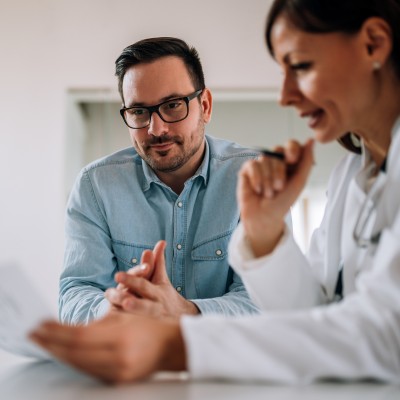 Der deutsche Krankenhausatlas - Was bringt die neue Online-Plattform?: Ärztin schaut gemeinsam mit männlichem Patienten auf Untersuchungsergebnisse auf einem Blatt Papier.