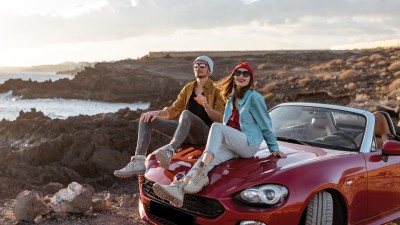 5 Tipps für die entspannte Fahrt in den Sommerurlaub: Paar mit Cabrio am Strand