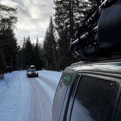 Blick aus dem Auto auf ein dahinter fahrendes Auto auf einer verschneiten Stra&szlig;e