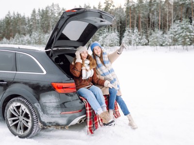 Neue Reifen-Regel - Das Alpine-Symbol kommt, die M+S-Kennzeichnung geht. : Zwei junge Frauen sitzen im Kofferraum ihres Autos in einer winterlichen Landschaft