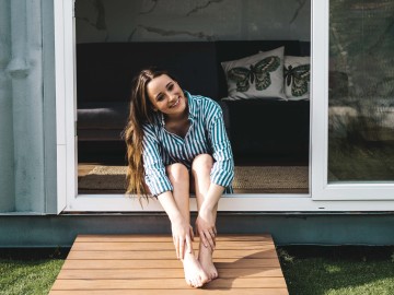 Tiny-House – ein Trend mit Zukunft?: Junge Frau sitzt vor Tiny House