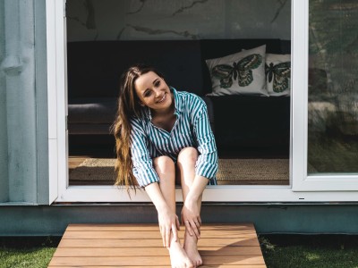 Tiny-House – ein Trend mit Zukunft?: Junge Frau sitzt vor Tiny House