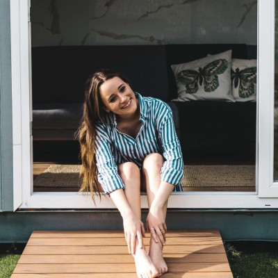 Tiny-House – ein Trend mit Zukunft?: Junge Frau sitzt vor Tiny House