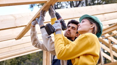 Immobilienwunsch - Wie geht es jetzt weiter?: Mann und Frau auf Baustelle bohren am Dachbalken