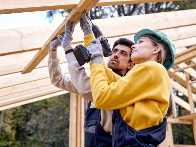 Immobilienwunsch - Wie geht es jetzt weiter?: Mann und Frau auf Baustelle bohren am Dachbalken