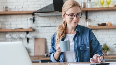 Bonus vom Fiskus - Wie Sie der Staat mit der Arbeitnehmersparzulage fürs Sparen belohnt: Frau berechnet Arbeitnehmersparzulage mit einem Taschenrechner und Laptop