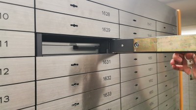 Bankschließfach - Sind Ihre Wertsachen dort ausreichend abgesichert?: Eine Hand &ouml;ffnet ein silbernes Bankschlie&szlig;fach mit einem Schl&uuml;ssel