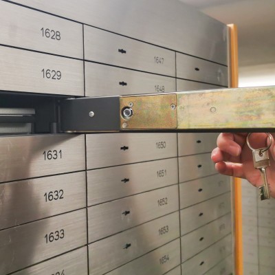 Bankschließfach - Sind Ihre Wertsachen dort ausreichend abgesichert?: Eine Hand &ouml;ffnet ein silbernes Bankschlie&szlig;fach mit einem Schl&uuml;ssel