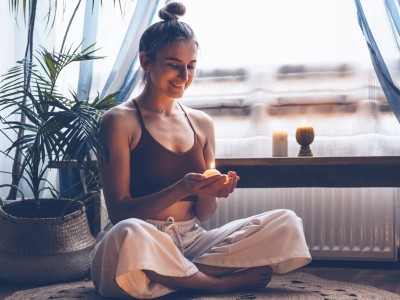 Frau macht Yoga mit Kerze in der Wohnung