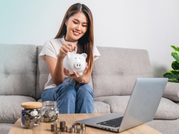 Interview - Das 3-Topf-Modell des Vermögensaufbaus: Junge Frau mit Sparschwein in der Hand sortiert ihr Geld