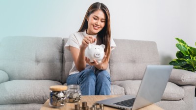 Interview - Das 3-Topf-Modell des Vermögensaufbaus: Junge Frau mit Sparschwein in der Hand sortiert ihr Geld