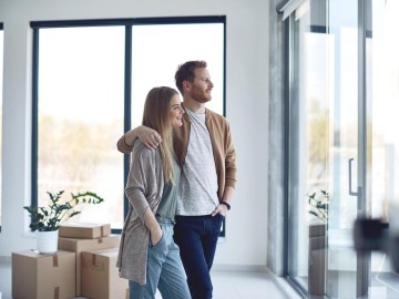 Riester-Rente - Jetzt noch abschließen oder auf das neue, geförderte Altersvorsorgedepot warten? : Paar schaut nach Umzug entspannt aus dem gro&szlig;em Wohnzimmerfenster