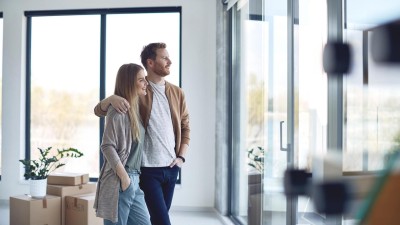 Riester-Rente - Jetzt noch abschließen oder auf das neue, geförderte Altersvorsorgedepot warten? : Paar schaut nach Umzug entspannt aus dem gro&szlig;em Wohnzimmerfenster