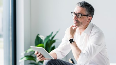 Was bedeutet die aktuelle Rentendebatte? Perspektiven für Ihre Altersvorsorge: Ein Mann schaut auf sein Tablett und denkt nach