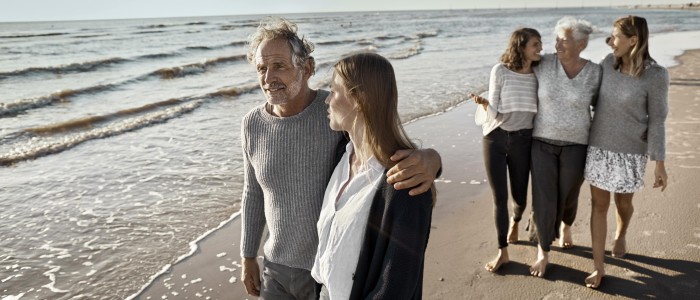 Fünf Menschen laufen am Strand entlang am Meer