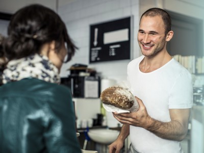 Bäckerei & Konditorei: Bäcker holt in Großbäckerei Brote aus dem Ofen
