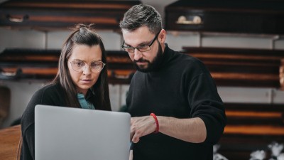 Bestatter: Bestatter mit einem Laptop in einem Raum mit Särgen