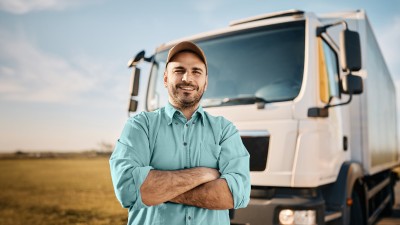 LKW-Versicherung: Lkw-Fahrer steht mit verschränkten Armen vor seinem Lastkraftwagen