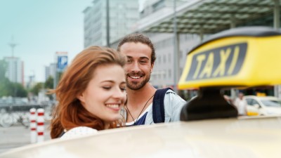 Taxiversicherung: Ein Paar hinter einem Taxischild auf einem Fahrzeug.