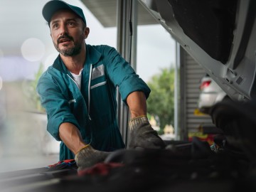 Kfz-Handel- und Handwerkversicherung: Ein Kfz-Mechniker arbeitet an einem Motor