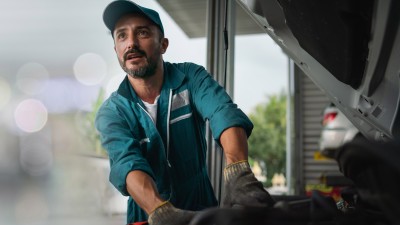 Kfz-Handel- und Handwerkversicherung: Ein Kfz-Mechniker arbeitet an einem Motor