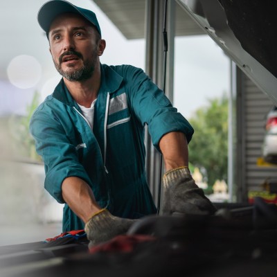 Kfz-Handel- und Handwerkversicherung: Ein Kfz-Mechniker arbeitet an einem Motor