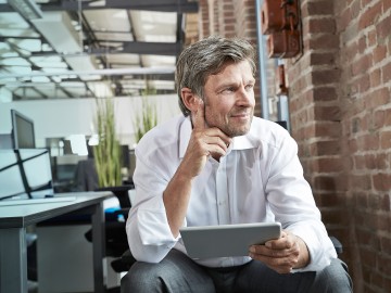 Cyber-Versicherung: Ein Mann mit Laptop blickt in die Ferne