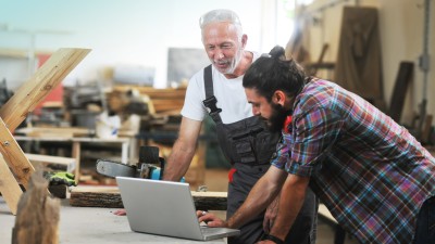 Gebäudeversicherung für Ihr Gewerbe: Zwei Handwerker in der Schreinerei am Laptop