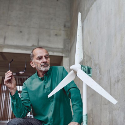 Windkraftanlagen-Versicherung: Mann schaut auf das Modell einer Windkraftanlage