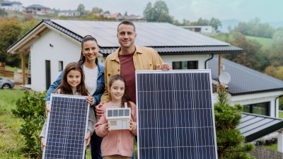 Photovoltaikversicherung: Familie mit Solarpanels vor Haus stehend