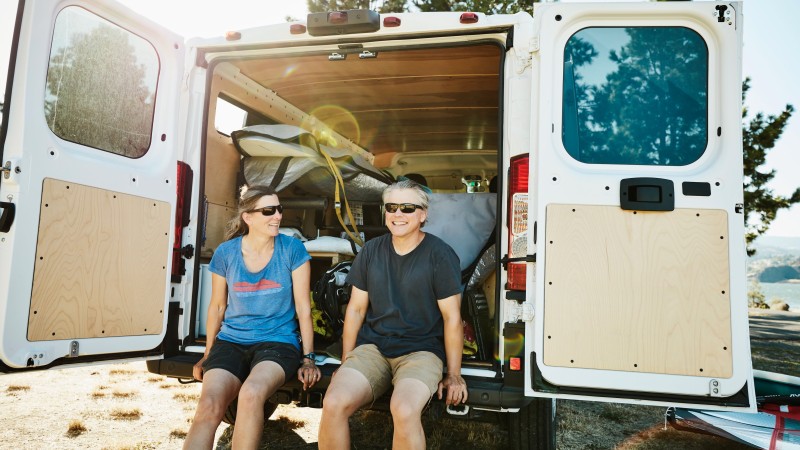 Ehepaar sitzt auf der Ladefläche eines Campers