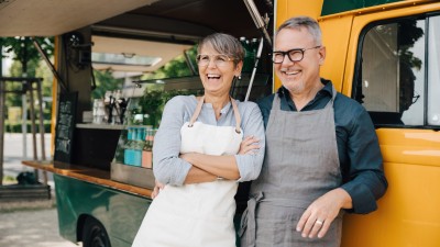 Unternehmer-Paar lachend vor ihrem Foodtruck
