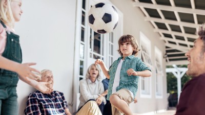 Private Haftpflichtversicherung: Familien schaut einem Kind beim Fussball jonglieren zu
